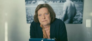 Movie still from “A Place to Fight For” (2023), directed by Romain Cogitore – An older woman is sitting in front of a picture; Close Up shot, High angle