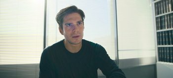 Movie still from “A Place to Fight For” (2023), directed by Romain Cogitore – A person sitting in a room; Close Up shot, Low angle