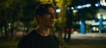 Movie still from “A Place to Fight For” (2023), directed by Romain Cogitore – A man in a black shirt is standing in the dark; Close Up shot, Over the shoulder angle