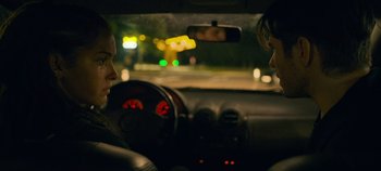 Movie still from “A Place to Fight For” (2023), directed by Romain Cogitore – A couple of people in a car at night time; Close Up shot, Over the shoulder angle