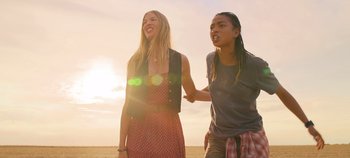 Movie still from “A Place to Fight For” (2023), directed by Romain Cogitore – Two young people holding hands while standing in a field; Medium shot, Low angle