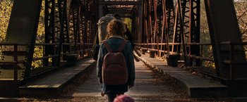 Movie still from “A Quiet Place” (2018), directed by John Krasinski – Two people walking across a bridge holding hands; Wide shot, Over the shoulder angle