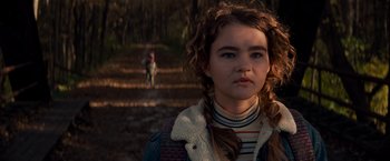 Movie still from “A Quiet Place” (2018), directed by John Krasinski – A young girl with a long braid is standing in a wooded area; Close Up shot, Low angle