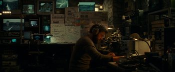 Movie still from “A Quiet Place” (2018), directed by John Krasinski – A man wearing headphones and sitting at a table; Medium shot, High angle