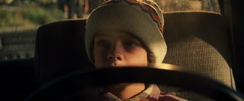 Movie still from “A Quiet Place” (2018), directed by John Krasinski – A young boy wearing a hat and holding a stick in his mouth; Close Up shot, High angle
