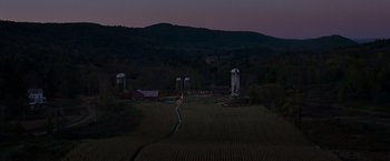Movie still from “A Quiet Place” (2018), directed by John Krasinski – An aerial view of a farm at night with silos in the background; Extreme Wide shot, High angle