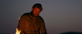 Movie still from “A Quiet Place” (2018), directed by John Krasinski – A man with a beard is standing in the dark; Medium shot, Low angle