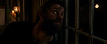 Movie still from “A Quiet Place” (2018), directed by John Krasinski – A man with a beard looking out of a window; Close Up shot, Low angle