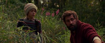 Movie still from “A Quiet Place” (2018), directed by John Krasinski – A man and a boy standing next to each other in the grass; Medium shot, Over the shoulder angle