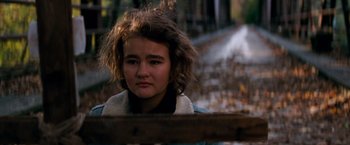 Movie still from “A Quiet Place” (2018), directed by John Krasinski – A young woman is standing in front of a wooden fence; Close Up shot, Low angle