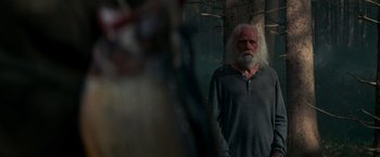 Movie still from “A Quiet Place” (2018), directed by John Krasinski – An old man with white hair standing in front of trees; Medium shot, Over the shoulder angle