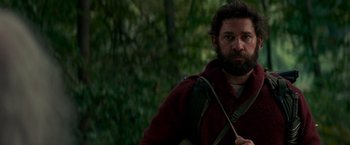 Movie still from “A Quiet Place” (2018), directed by John Krasinski – A man with a beard is holding a backpack; Medium shot, Low angle