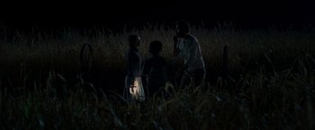 Movie still from “A Quiet Place” (2018), directed by John Krasinski – A group of people standing next to each other in a field at night; Wide shot, High angle