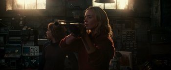 Movie still from “A Quiet Place” (2018), directed by John Krasinski – A woman holding a video camera in a room with other people; Medium shot, Low angle