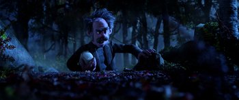 Movie still from “A Shaun the Sheep Movie: Farmageddon” (2019), directed by Will Becher – A man holding an apple in a forest; Wide shot, High angle