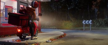 Movie still from “A Shaun the Sheep Movie: Farmageddon” (2019), directed by Will Becher – A person sitting on a scooter on the side of the road; Wide shot, Over the shoulder angle