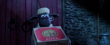 Movie still from “A Shaun the Sheep Movie: Farmageddon” (2019), directed by Will Becher – A stuffed sheep sitting on top of a box of pizza; Medium shot, High angle