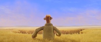 Movie still from “A Shaun the Sheep Movie: Farmageddon” (2019), directed by Will Becher – A stuffed animal wearing a sweater sitting in a field; Wide shot, Low angle