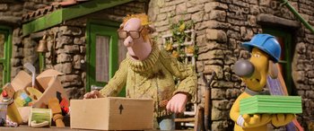 Movie still from “A Shaun the Sheep Movie: Farmageddon” (2019), directed by Will Becher – A man in a yellow sweater holding an open box; Medium shot, Low angle