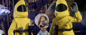 Movie still from “A Shaun the Sheep Movie: Farmageddon” (2019), directed by Will Becher – A group of yellow statues with a man in a helmet; Medium shot, High angle