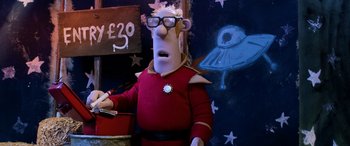 Movie still from “A Shaun the Sheep Movie: Farmageddon” (2019), directed by Will Becher – A man in a red shirt is standing in front of a wall; Medium shot, Low angle