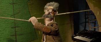 Movie still from “A Shaun the Sheep Movie: Farmageddon” (2019), directed by Will Becher – A man with a long beard holding a rope in front of a green wall; Close Up shot, Low angle