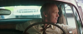 Movie still from “The Founder” (2016), directed by John Lee Hancock – A man sitting in the drivers seat of a car; Close Up shot, Over the shoulder angle