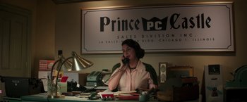 Movie still from “The Founder” (2016), directed by John Lee Hancock – A woman sitting at a desk talking on the phone; Medium shot, High angle