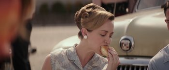 Movie still from “The Founder” (2016), directed by John Lee Hancock – A woman eating a hot dog on top of a bun; Close Up shot, Over the shoulder angle