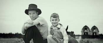 Movie still from “The Founder” (2016), directed by John Lee Hancock – A man and a boy sitting next to each other on a field; Close Up shot, Low angle