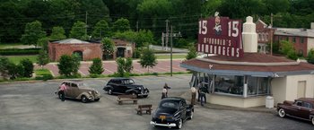 Movie still from “The Founder” (2016), directed by John Lee Hancock – An old car parked in front of a restaurant; Extreme Wide shot, High angle