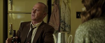 Movie still from “The Founder” (2016), directed by John Lee Hancock – A man wearing a suit and tie in front of a teapot; Medium shot, Over the shoulder angle