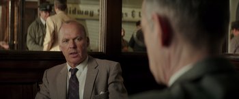 Movie still from “The Founder” (2016), directed by John Lee Hancock – A man in a suit and tie in front of a mirror; Close Up shot, Over the shoulder angle