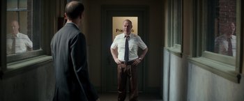 Movie still from “The Founder” (2016), directed by John Lee Hancock – A man standing in front of another man in front of a door; Medium shot, Low angle