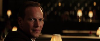 Movie still from “The Founder” (2016), directed by John Lee Hancock – A man's face with a lamp in the background; Close Up shot, Over the shoulder angle