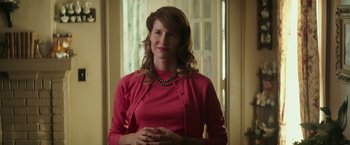Movie still from “The Founder” (2016), directed by John Lee Hancock – A woman in a pink sweater standing in front of a window; Medium shot, Over the shoulder angle