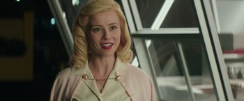 Movie still from “The Founder” (2016), directed by John Lee Hancock – A woman with blonde hair and a pink jacket smiling; Close Up shot, Over the shoulder angle