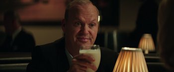 Movie still from “The Founder” (2016), directed by John Lee Hancock – A person holding a glass of milk; Close Up shot, Over the shoulder angle