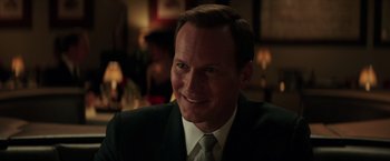 Movie still from “The Founder” (2016), directed by John Lee Hancock – A person wearing a suit and tie; Close Up shot, Over the shoulder angle