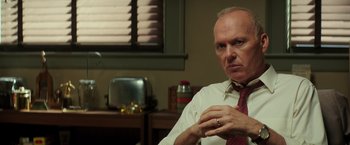 Movie still from “The Founder” (2016), directed by John Lee Hancock – An older man wearing a red tie sitting in front of a window; Close Up shot, Over the shoulder angle