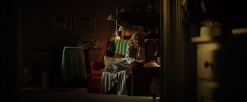 Movie still from “The Founder” (2016), directed by John Lee Hancock – A woman sitting on top of a red couch in a living room; Wide shot, Low angle