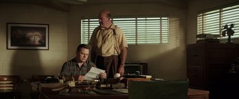 Movie still from “The Founder” (2016), directed by John Lee Hancock – A man standing next to another man holding papers; Medium shot, Low angle