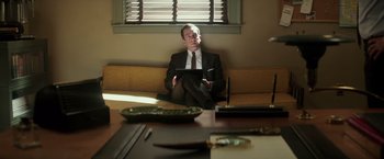 Movie still from “The Founder” (2016), directed by John Lee Hancock – A man sitting at a table with a tablet in his hands; Medium shot, Low angle