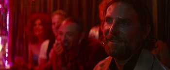 Movie still from “A Star Is Born” (2018), directed by Bradley Cooper – A man with a beard is smiling for the camera; Close Up shot, Over the shoulder angle