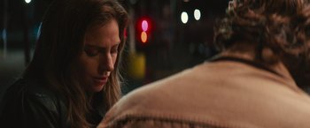 Movie still from “A Star Is Born” (2018), directed by Bradley Cooper – A person sitting on a chair near a street light; Close Up shot, Over the shoulder angle
