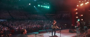 Movie still from “A Star Is Born” (2018), directed by Bradley Cooper – A man with a guitar in front of an audience; Wide shot, High angle