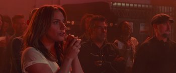 Movie still from “A Star Is Born” (2018), directed by Bradley Cooper – A woman eating a piece of food while sitting in front of other people; Close Up shot, Over the shoulder angle