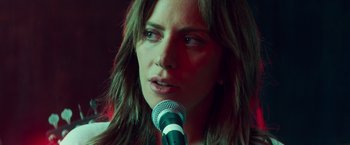 Movie still from “A Star Is Born” (2018), directed by Bradley Cooper – A person holding a microphone; Close Up shot, Over the shoulder angle