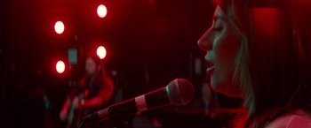 Movie still from “A Star Is Born” (2018), directed by Bradley Cooper – A woman is singing into a microphone in front of a crowd; Close Up shot, Low angle