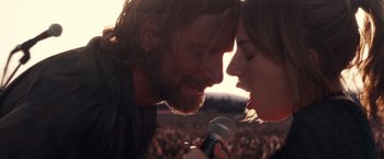 Movie still from “A Star Is Born” (2018), directed by Bradley Cooper – A man and a woman are holding a microphone; Close Up shot, Low angle